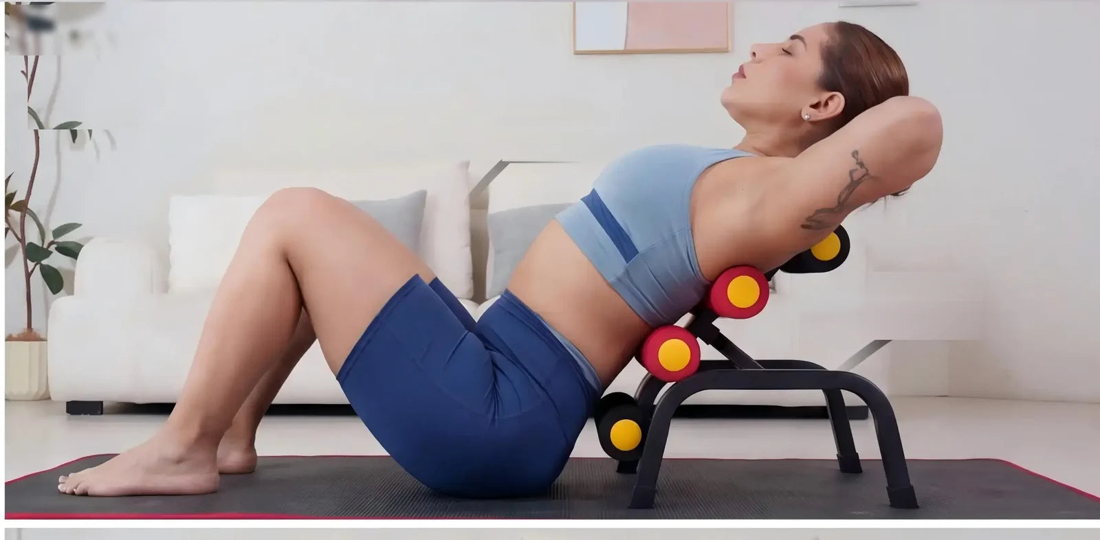 A person reclining against the Magic BB frame's rollers mid core curl, feet on the mat